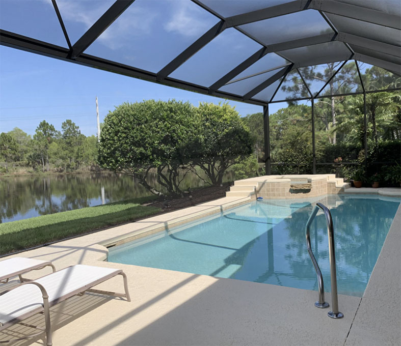 A spacious outdoor living area with a screened porch, outdoor furniture, and greenery