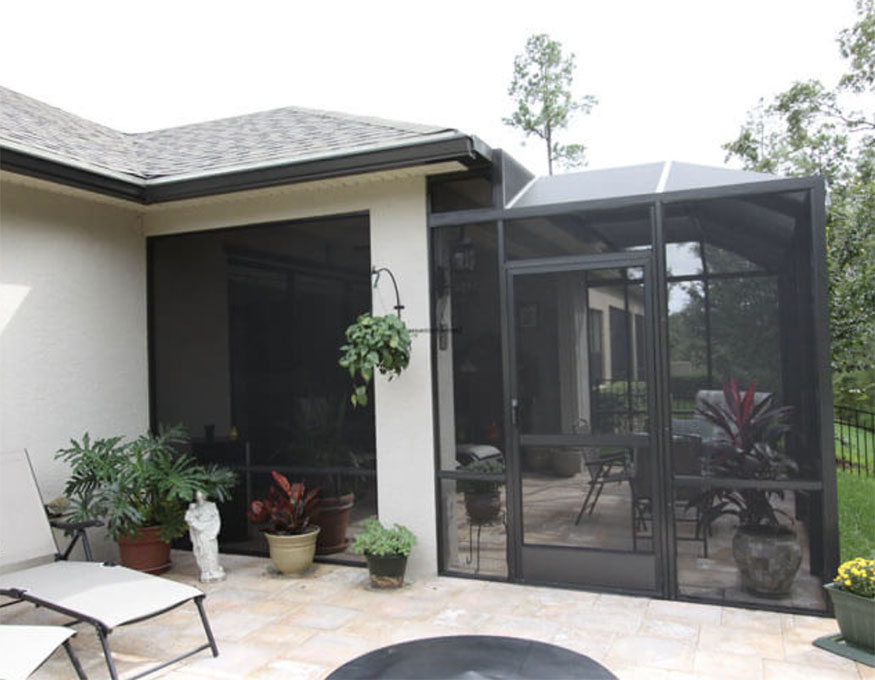 A spacious outdoor living area  in Florida with a screened porch, outdoor furniture and flowers 