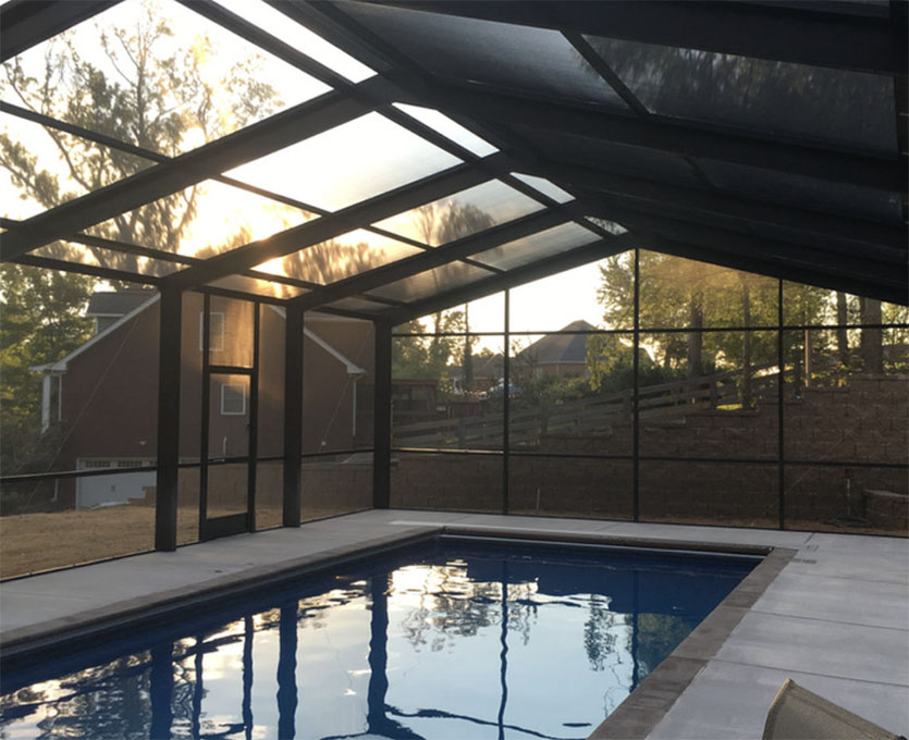 An image of a pool enclosure installation with a view of the pool and surrounding greenery